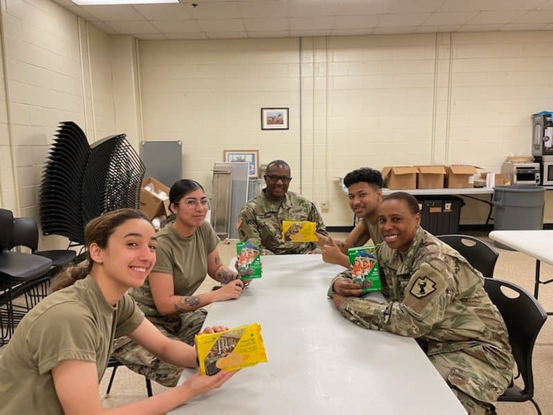 service members holding boxes of Girl Scout cookies
