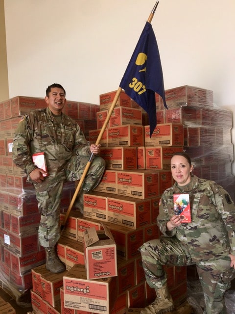 service members holding boxes of Girl Scout cookies