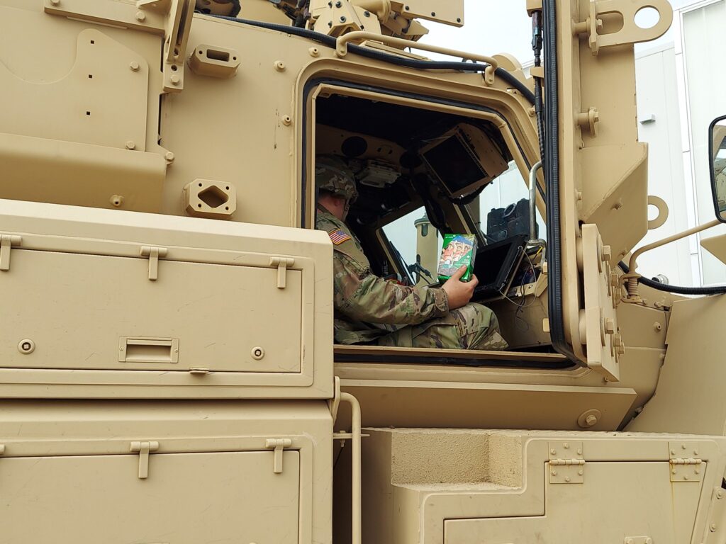 service members in tank holding a box of Girl Scout cookies