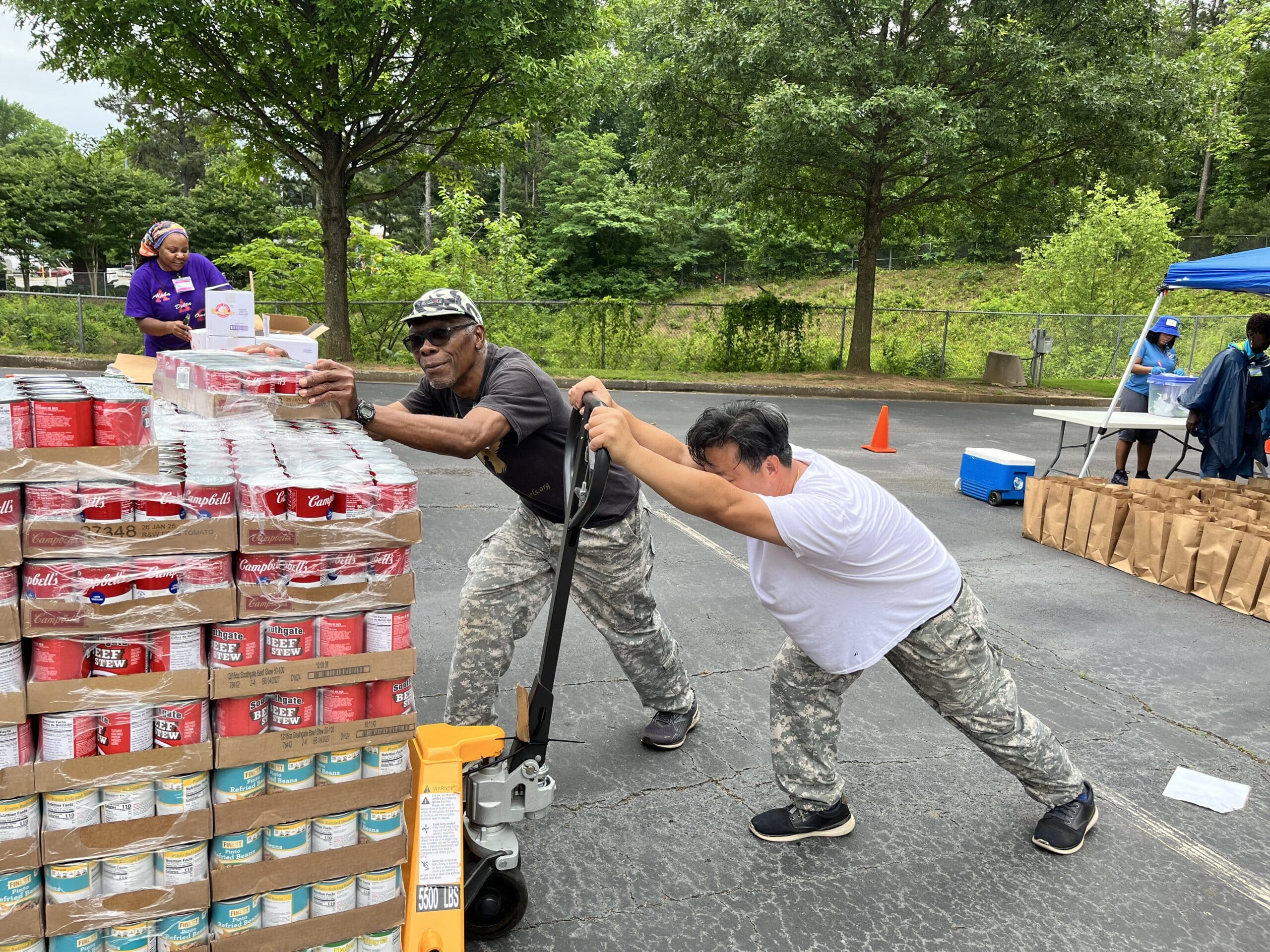Two volunteers transporting a loaded food cart 