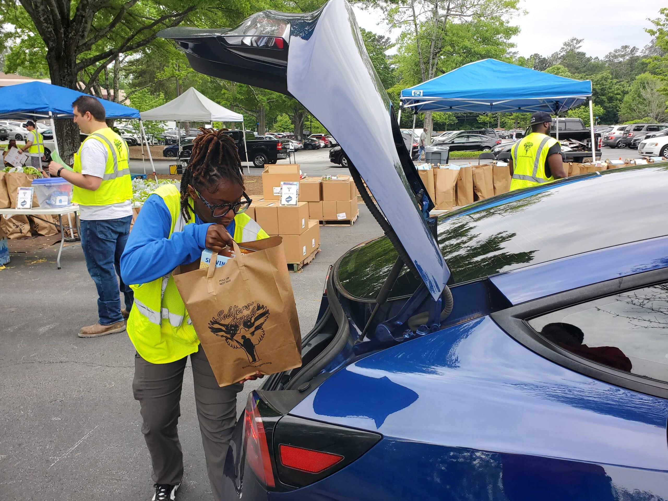 A volunteer loading groceries into a car at an outdoor Soldiers' Angels event