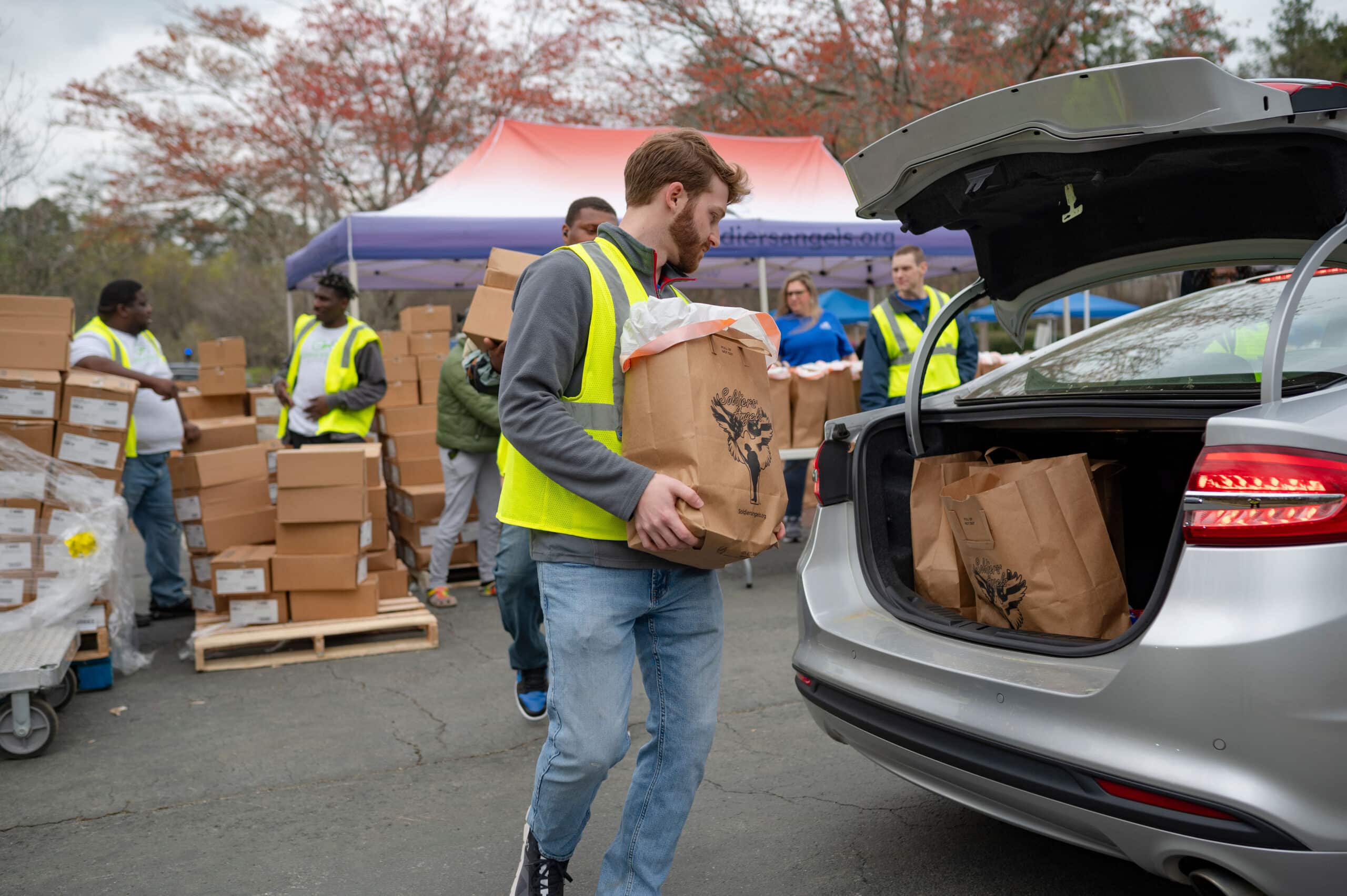 Volunteer loading groceries into a car at a food distribution event