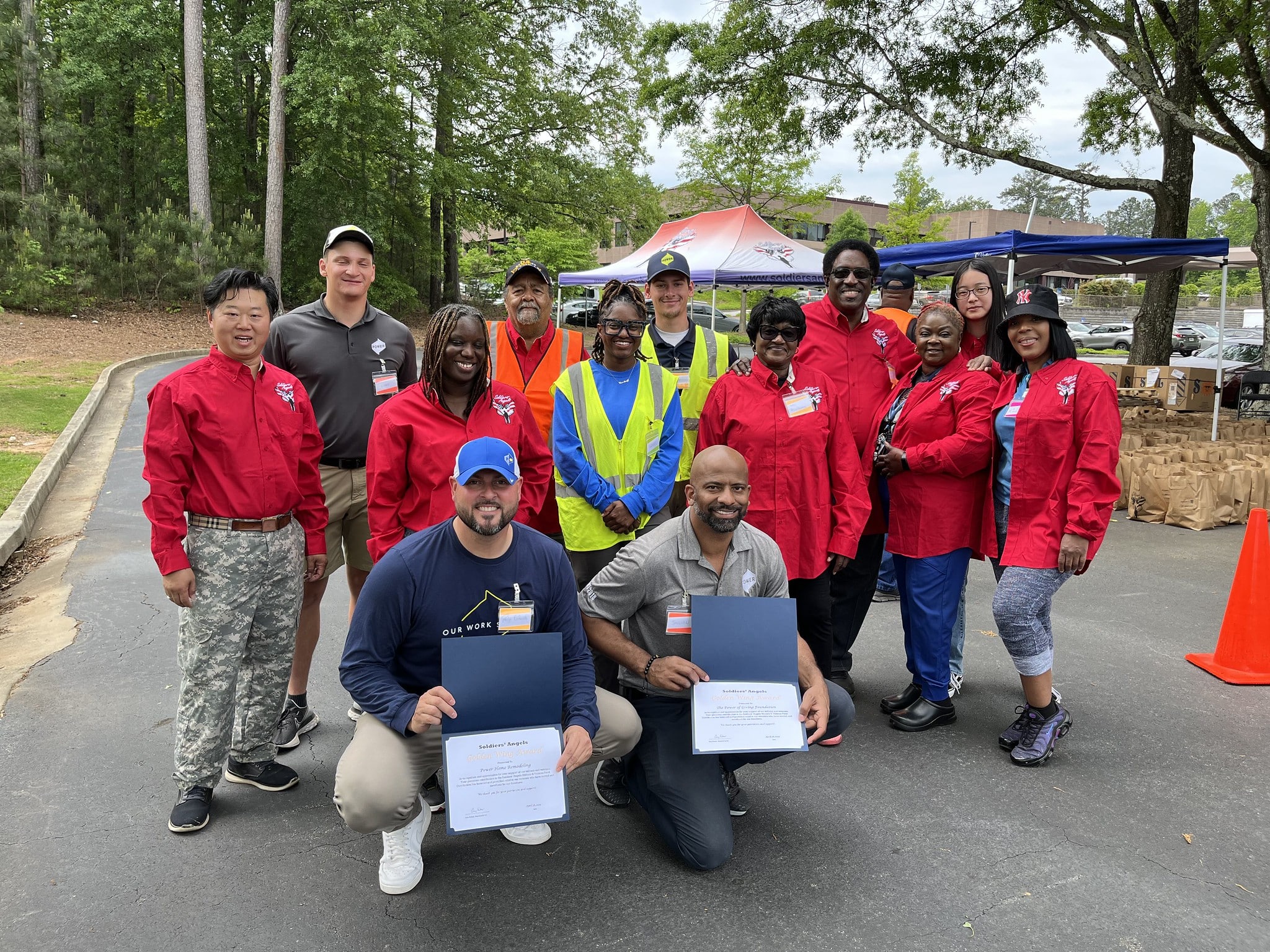 Soldiers' Angels volunteers in red shirts posing outdoors at a food distribution event in Atlanta, Georgia