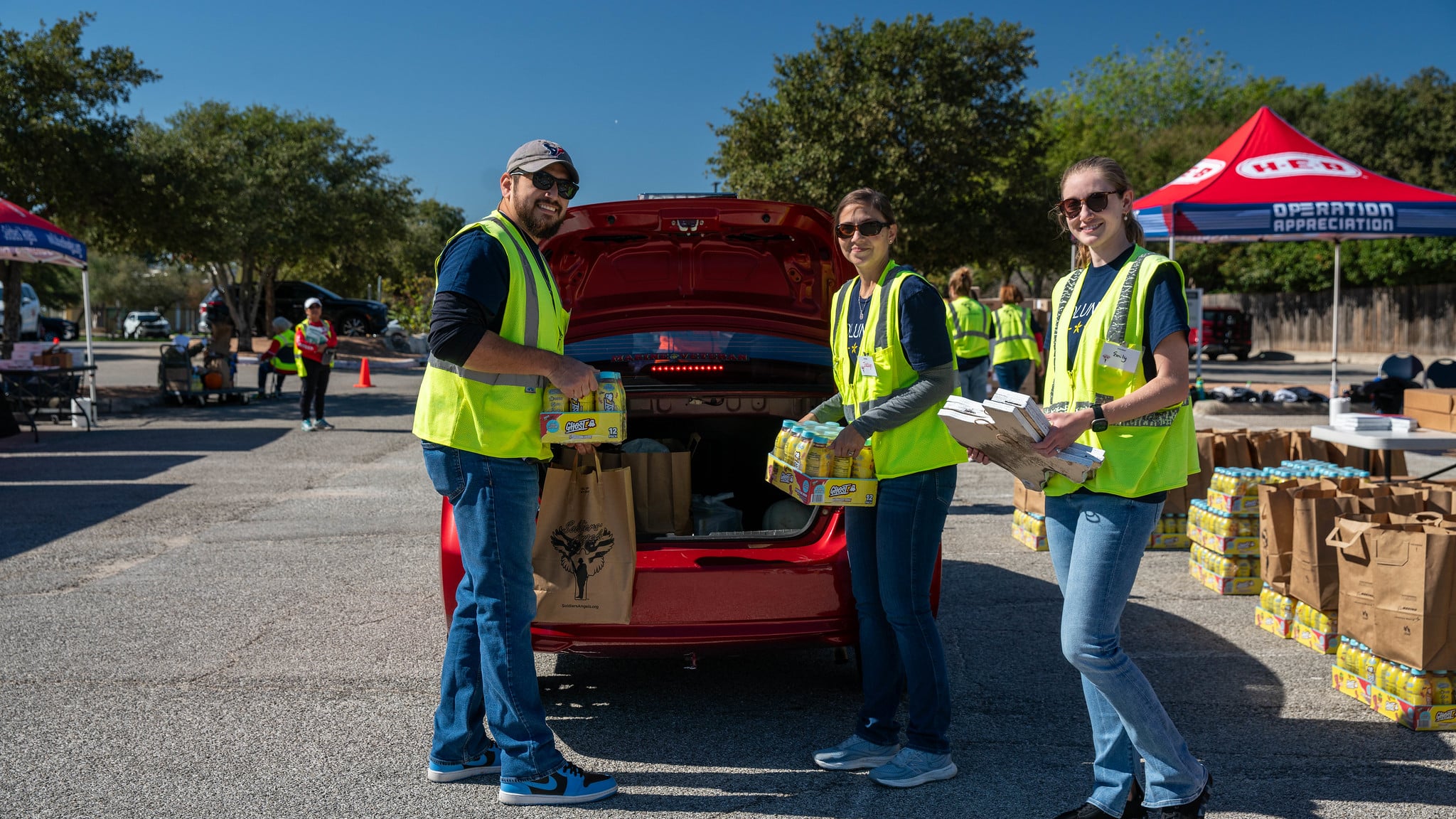 Soldiers' Angels volunteers in red shirts posing outdoors at a food distribution event in Atlanta, Georgia